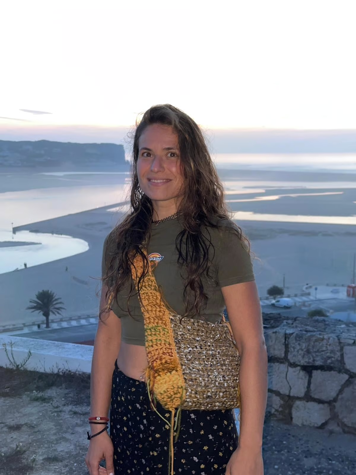 Evgenia on the coast at dusk, with a crochet bag
